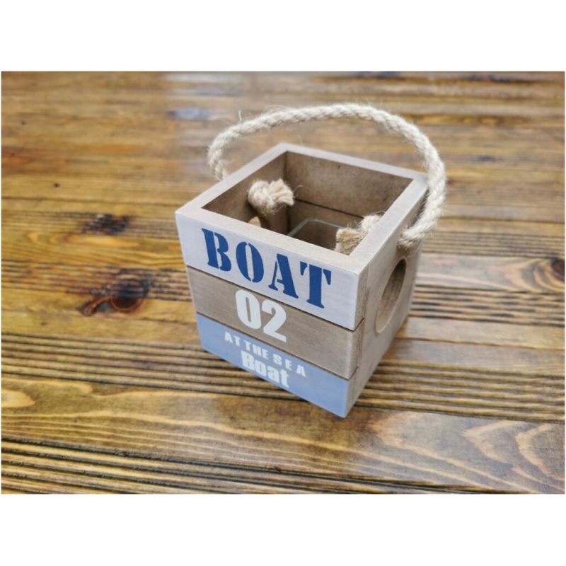 Eine kleine Holzbox mit rustikalem Finish und Seilgriff. Die Box ist mit den Worten „BOAT 02 AT THE SEA BOAT“ in blau-weißem Text verziert. Sie dient auch als charmanter Teelichthalter mit Tau und steht auf einer Holzoberfläche mit natürlicher, verwitterter Textur.