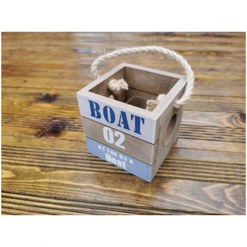 Eine kleine Holzbox mit rustikalem Finish und Seilgriff. Die Box ist mit den Worten „BOAT 02 AT THE SEA BOAT“ in blau-weißem Text verziert. Sie dient auch als charmanter Teelichthalter mit Tau und steht auf einer Holzoberfläche mit natürlicher, verwitterter Textur.