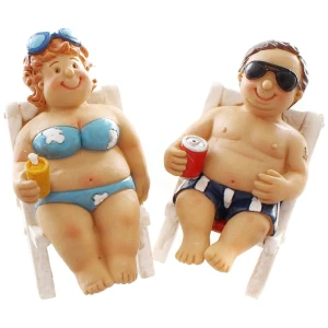 Zwei Tonfiguren eines glücklichen Urlauberpaares, das auf Liegestühlen faulenzt. Die weibliche Figur, die einen blauen Bikini und eine Sonnenbrille auf dem Kopf trägt, hält ein Getränk mit einem Strohhalm. Die männliche Figur trägt Badehose und Sonnenbrille und hält eine Getränkedose. Beide haben ein Lächeln im Gesicht.