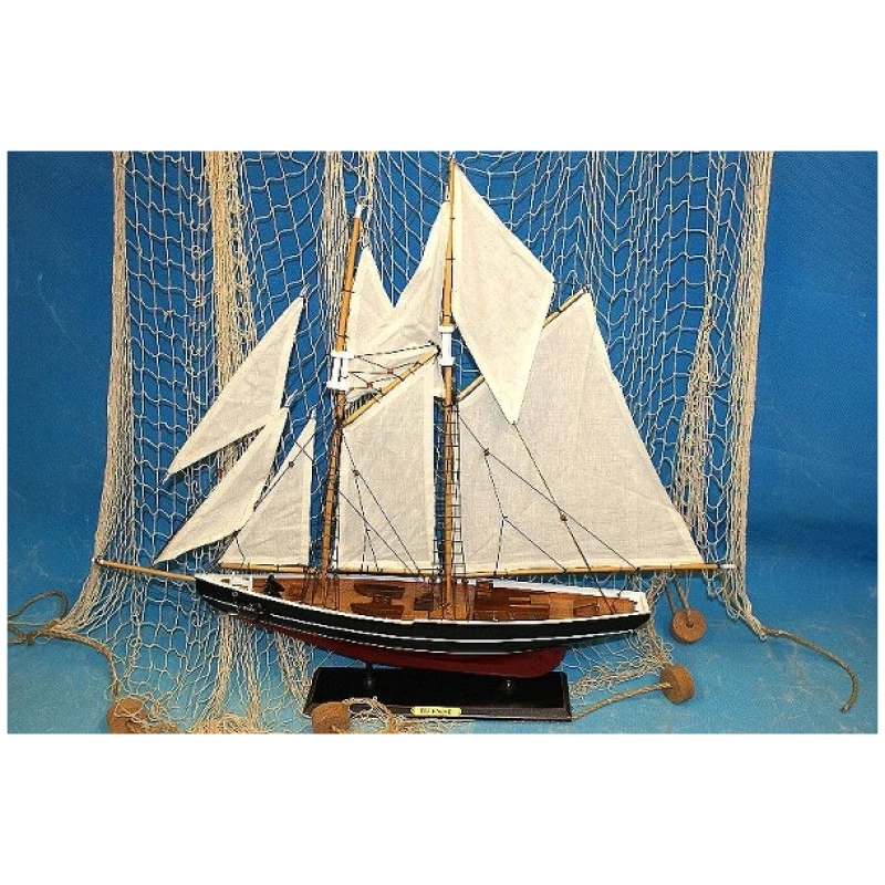 Vor einem Netzhintergrund wird ein detailliertes Modell eines Segelschiffs, bekannt als Segler 2 Master 76x66cm Holz, mit weißen Segeln und dunklem Holzrumpf ausgestellt. Das Schiff ruht auf einem schwarzen Ständer mit der Aufschrift „Schoner“. Der Hintergrund ist blau und unterstreicht das nautische Thema.