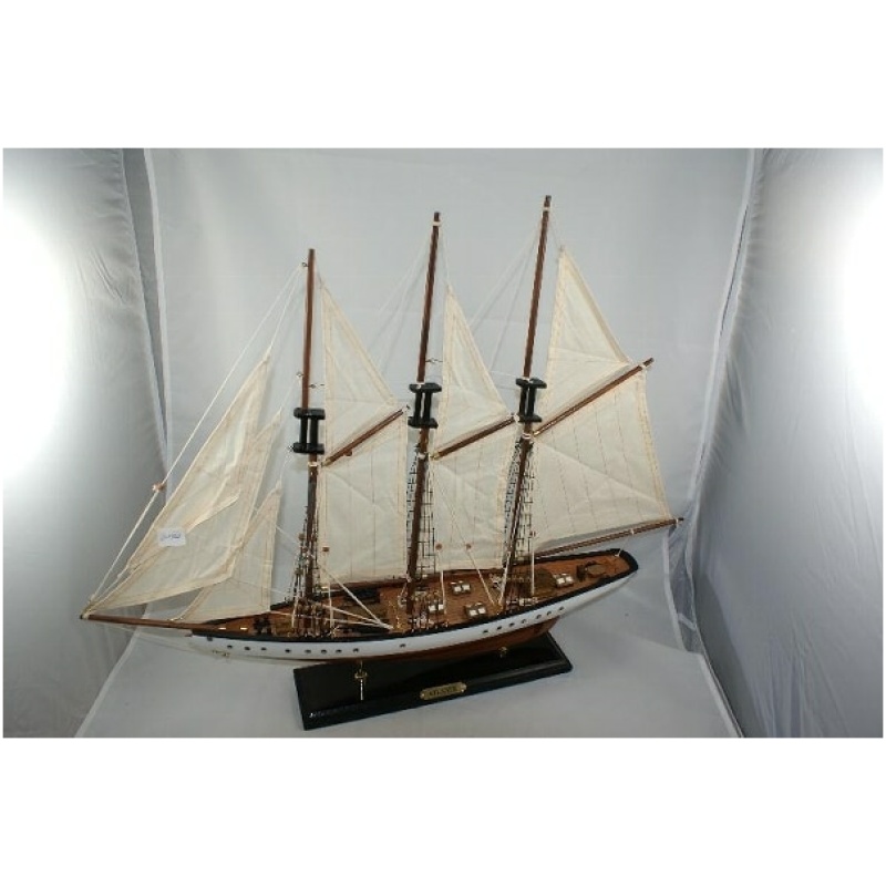 Ein detailliertes Modell eines Dreimastschoners (Segelboot 3 Master) ca. 72 x 12 x 57 cm, ausgestellt auf einem schwarzen Ständer. Das Schiff verfügt über weiße Segel, Holzmasten und eine aufwendige Takelage. Der Hintergrund ist schlicht und gut beleuchtet, was die Handwerkskunst des Modells hervorhebt.