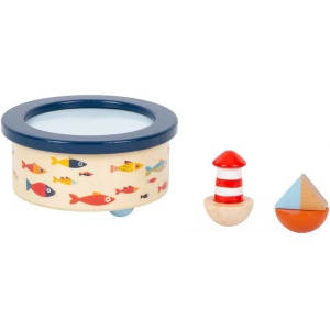 Ein Holzspielzeugset mit einer Trommel mit blauem Rand und bunten Fischen auf der Seite, einem rot-weiß gestreiften Leuchtturm und einem dreieckigen Segelboot mit einem blau-orangefarbenen Spaltdesign. Das Set enthält außerdem eine bezaubernde Spieluhr Großer Ozean (12 x 12 x 10 cm), die die Spielzeit mit herrlichen Melodien füllt.