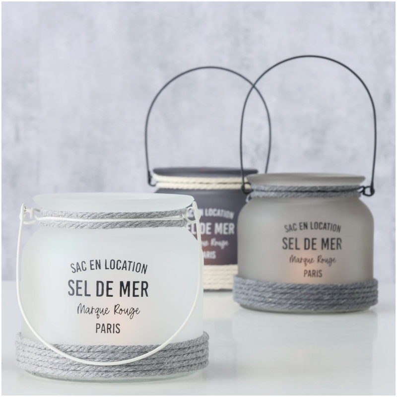 Exklusives Highline Windlicht Seldemer, Beige, Grau, Weiss Drei Laternen aus Milchglas mit Seilakzenten werden vor einem hellgrauen Hintergrund präsentiert. Die Laternen mit der Aufschrift „Sac en Location Sel de Mer Marque Rouge Paris“ und Griffen zum Tragen versprühen einen rustikalen, nautischen Charme. Perfekt als Highline Dekoaufsteller Saily oder um jeder Umgebung Flair zu verleihen.