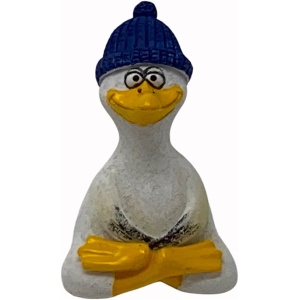 Eine kleine Skulptur einer Ente mit verschränkten Armen, weiß bemalt mit gelbem Schnabel und Flossen. Die Poly Yoga Möwe mit Mütze erinnert an eine fröhliche Möwe, trägt eine strukturierte blaue Beanie und hat große Augen und ein breites Lächeln. Der Hintergrund ist schlicht weiß.