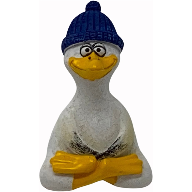 Eine kleine Skulptur einer Ente mit verschränkten Armen, weiß bemalt mit gelbem Schnabel und Flossen. Die Poly Yoga Möwe mit Mütze erinnert an eine fröhliche Möwe, trägt eine strukturierte blaue Beanie und hat große Augen und ein breites Lächeln. Der Hintergrund ist schlicht weiß.