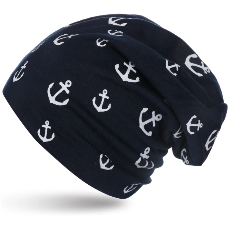 Eine marineblaue Beanie mit lockerer Passform, verziert mit einem Muster aus weißen Ankersymbolen. Die Beanie wirkt weich und gemütlich, mit einem lässigen maritimen Design. Sie ist vor einem schlichten weißen Hintergrund fotografiert.