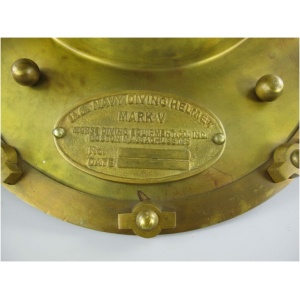 Nahaufnahme einer Messingplatte auf einem Taucherhelm Messing brüniert H.47x50cm mit der Aufschrift „MARK V“. Auf der Platte steht außerdem „Morse Diving Equipment Co. Inc, Boston, Massachusetts, U.S.A.“ und es sind Felder für „Nr.“ und „Datum“ vorhanden. Die umgebenden Bolzen und die Helmoberfläche sind sichtbar.