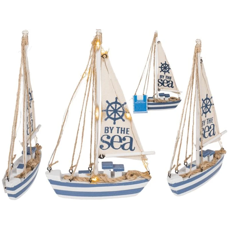 Vier kleine dekorative Segelboote mit weißen Segeln und blauem Rumpf. Jedes Segelboot ist mit dem Satz „BY THE SEA“ und einem Steuerrad auf dem Segel verziert und mit Lichterketten, nautischen Seilen und einem Hauch von Glitterkugeln, Maritim, auf Sockel mit tollen Motiven für zusätzliches Funkeln geschmückt.