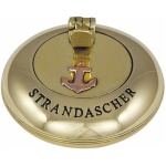 Ein rundes, goldenes Objekt mit der Gravur „STRANDASCHER“. Der aufklappbare Deckel ist mit einem kleinen Anker-Emblem verziert und verfügt über einen eleganten Automatik-Verschluss.