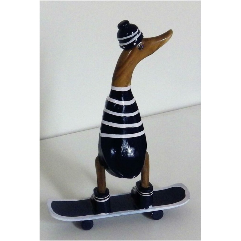 Die Skulptur „Ente auf Skateboard aus Bambus blau/weiss ca 21x10 cm Höhe 28 cm“ ist eine hölzerne Ente, die in schwarz-weiß gestreifte Kleidung, inklusive Beanie, gekleidet ist und auf einem Skateboard mit schwarzen Rädern steht. Die gesamte Figur steht auf einer flachen, weißen Oberfläche.