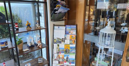 Vitrine mit Souvenirs, Postkarten und Informationsmaterial in einem Geschäft. Bietet eine Vielzahl von Andenken und touristischen Informationen.