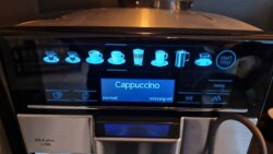 Nahaufnahme der Benutzeroberfläche einer Kaffeemaschine, auf der verschiedene Getränkeoptionen mit Symbolen angezeigt werden, darunter Cappuccino, Espresso und Milchschaum. Die ausgewählte Option ist „Cappuccino“, mit Einstellungen für „normale“ Stärke und „mittelgroß“, damit Sie Ihre Gäste verwöhnen können.
